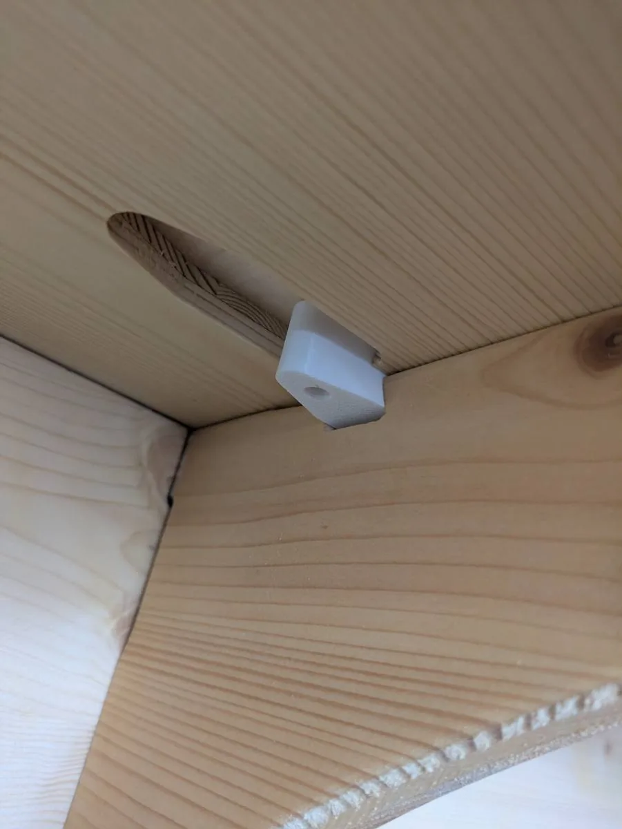 Clip blanc glissé dans la rainure entre deux panneaux de pin