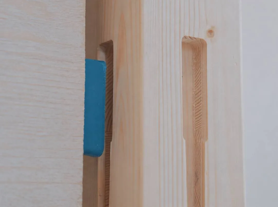 Clip bleu inséré dans la rainure verticale d'un panneau de bois