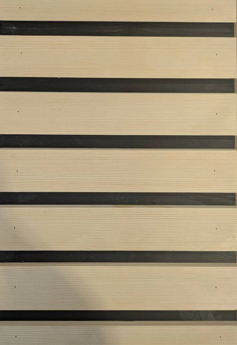 Façade en tasseaux de bois clair séparés par de fines bandes noires